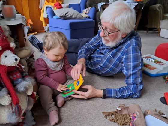 Willi und Enkelkind begucken sich ein erstes Buch